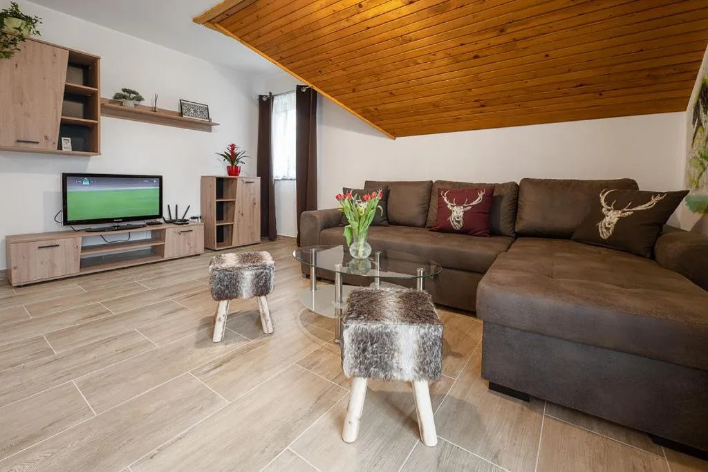 Dnevni prostor apartmaja z balkonom pod lesenim stropom