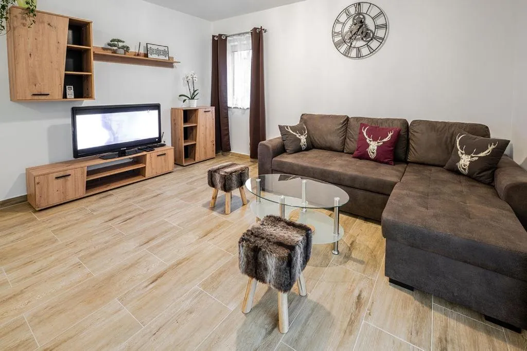 Dnevni prostor apartmaja s teraso s kotno sedežno garnituro in televizorjem